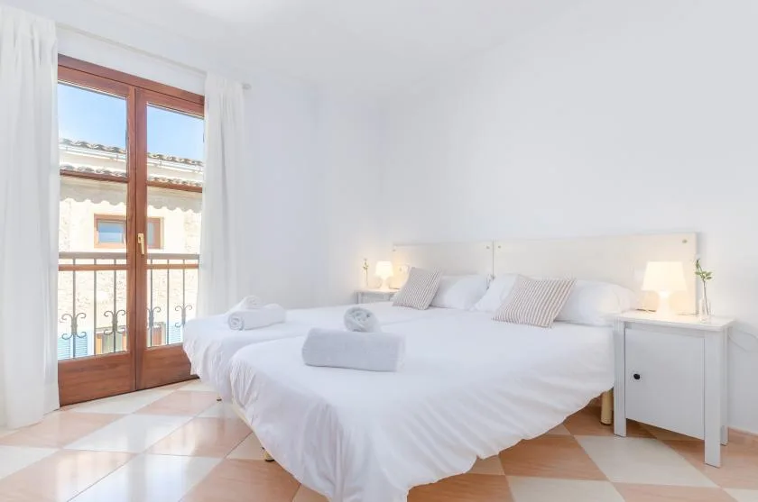 Un dormitorio luminoso con una cama grande y puertas de cristal que dan a un balcón.