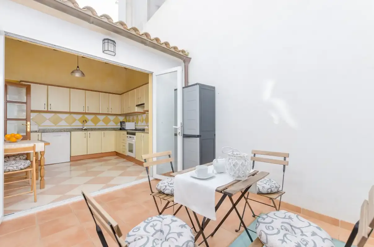 Un comedor al aire libre con mesa y sillas junto a una cocina.