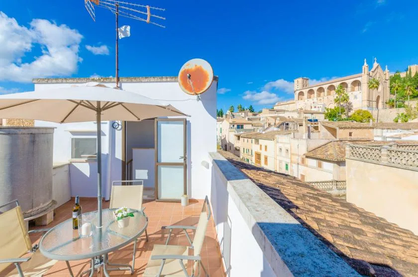 Una terraza en la azotea con asientos al aire libre da a una ciudad soleada y edificios históricos.