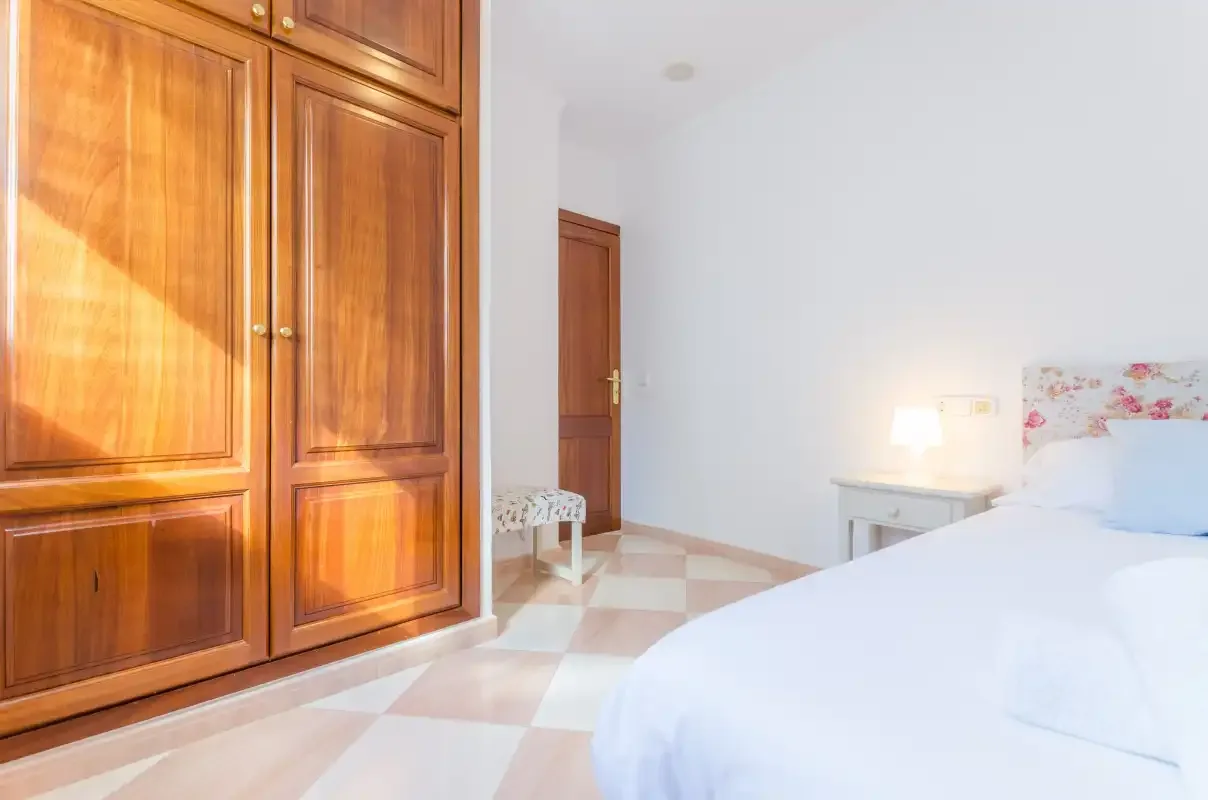 Dormitorio con un armario grande de madera y una cama.