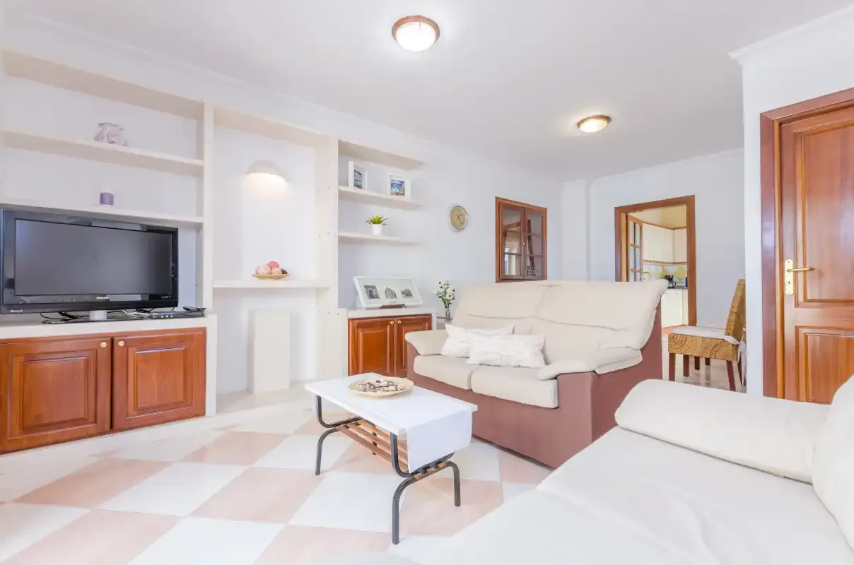 Una sala de estar luminosa con estantes empotrados, un televisor y asientos.