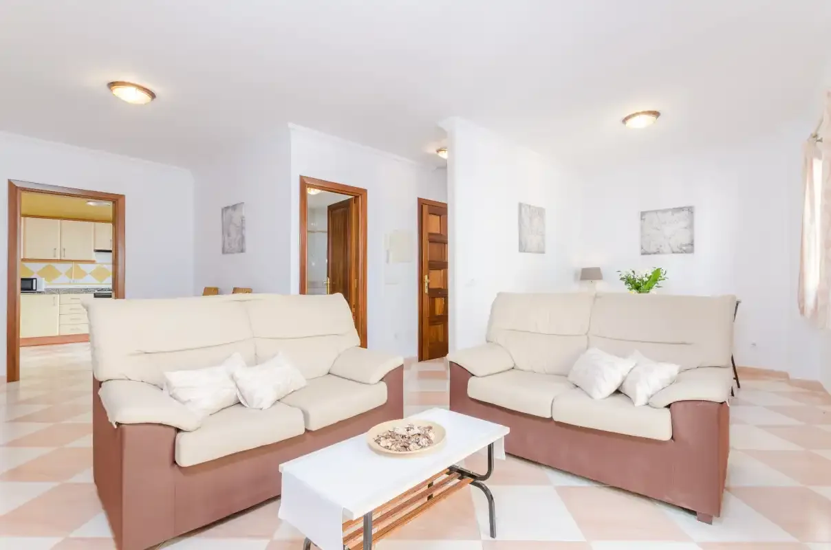 Una sala de estar luminosa con dos zonas de asientos y una mesa de centro baja.