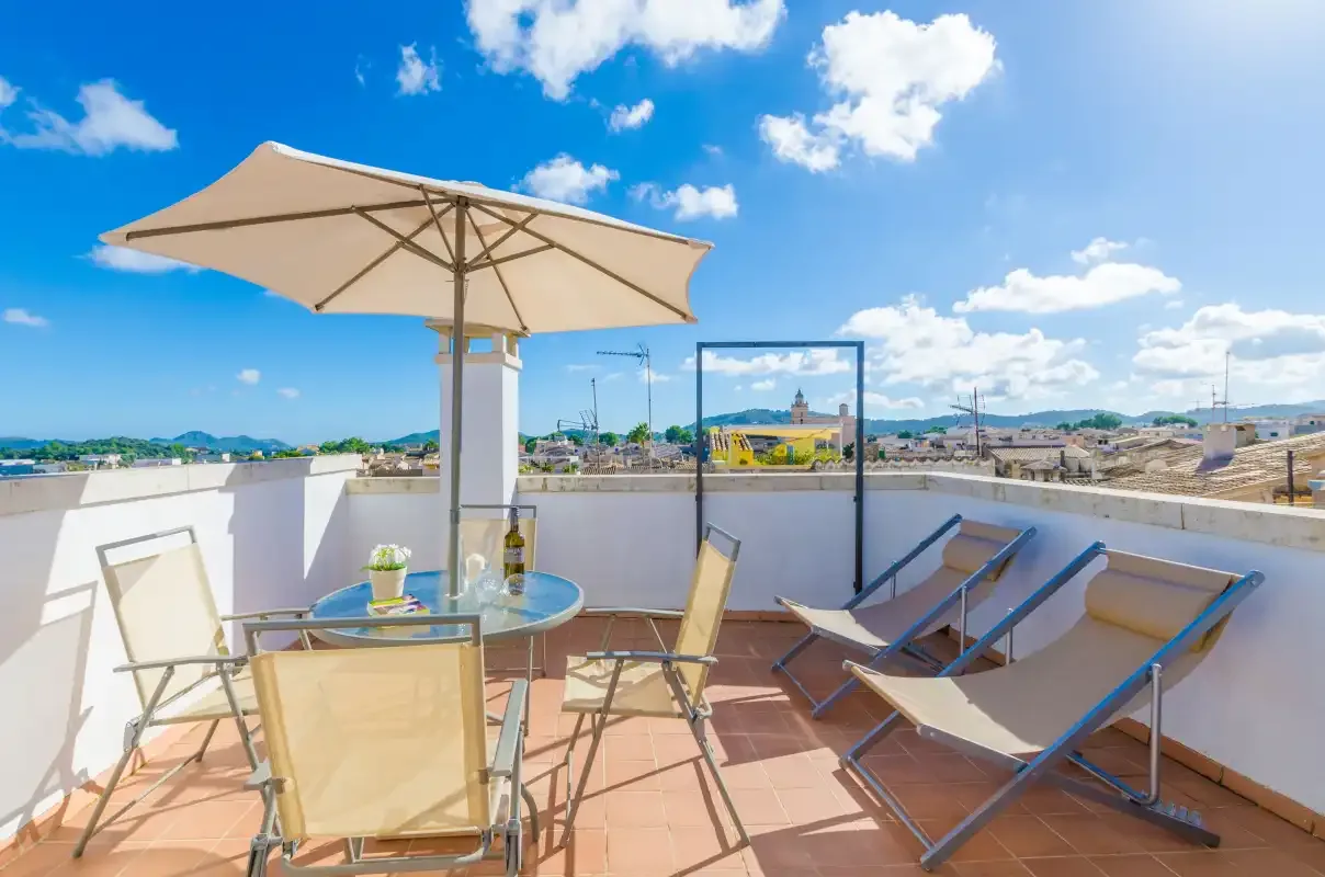 Una terraza en la azotea con asientos y una sombrilla grande ofrece vistas del pueblo.