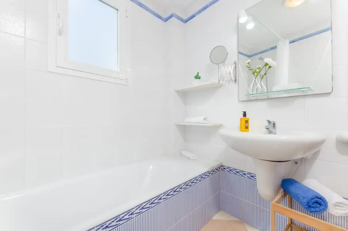 Un baño alicatado con bañera, lavabo y espejo de pared.