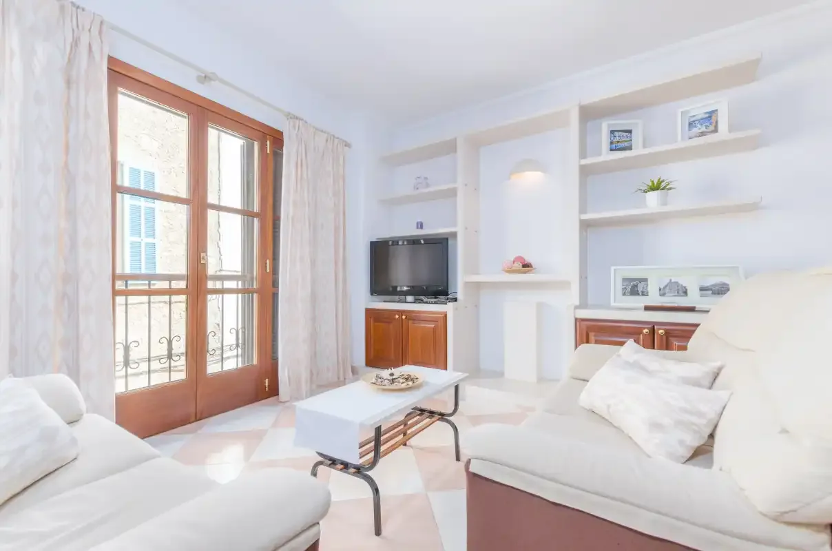 Una sala de estar luminosa con asientos, un televisor y estanterías empotradas.