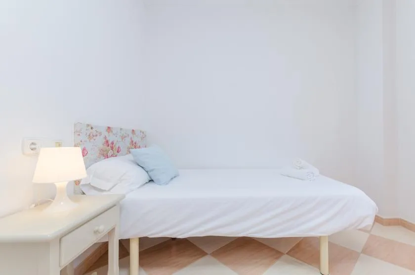 Un dormitorio con una cama blanca y una mesita de noche.