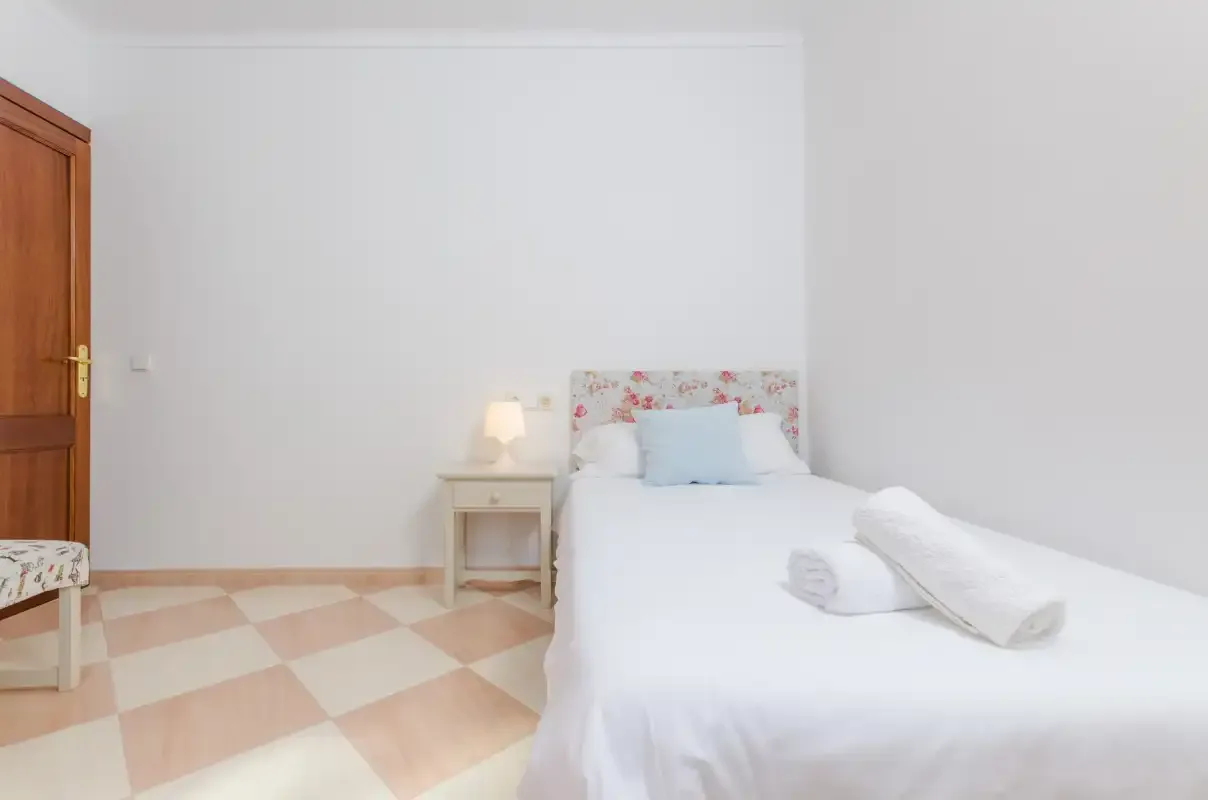 Un dormitorio con una cama bien arreglada y una pequeña mesita de noche.