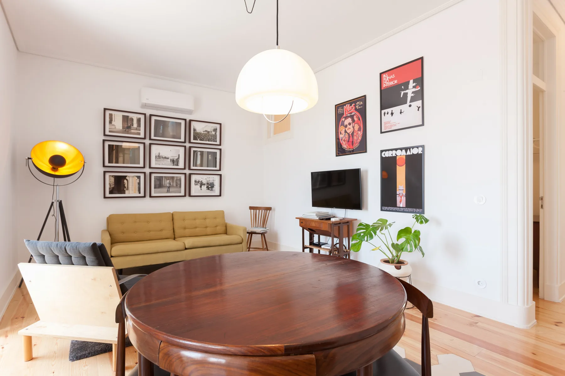A living room with a round wooden table, seating, and framed wall art.