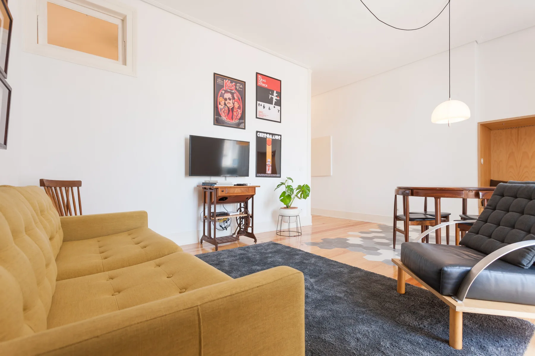 Una sala luminosa tiene asientos, un televisor y una mesa de comedor.