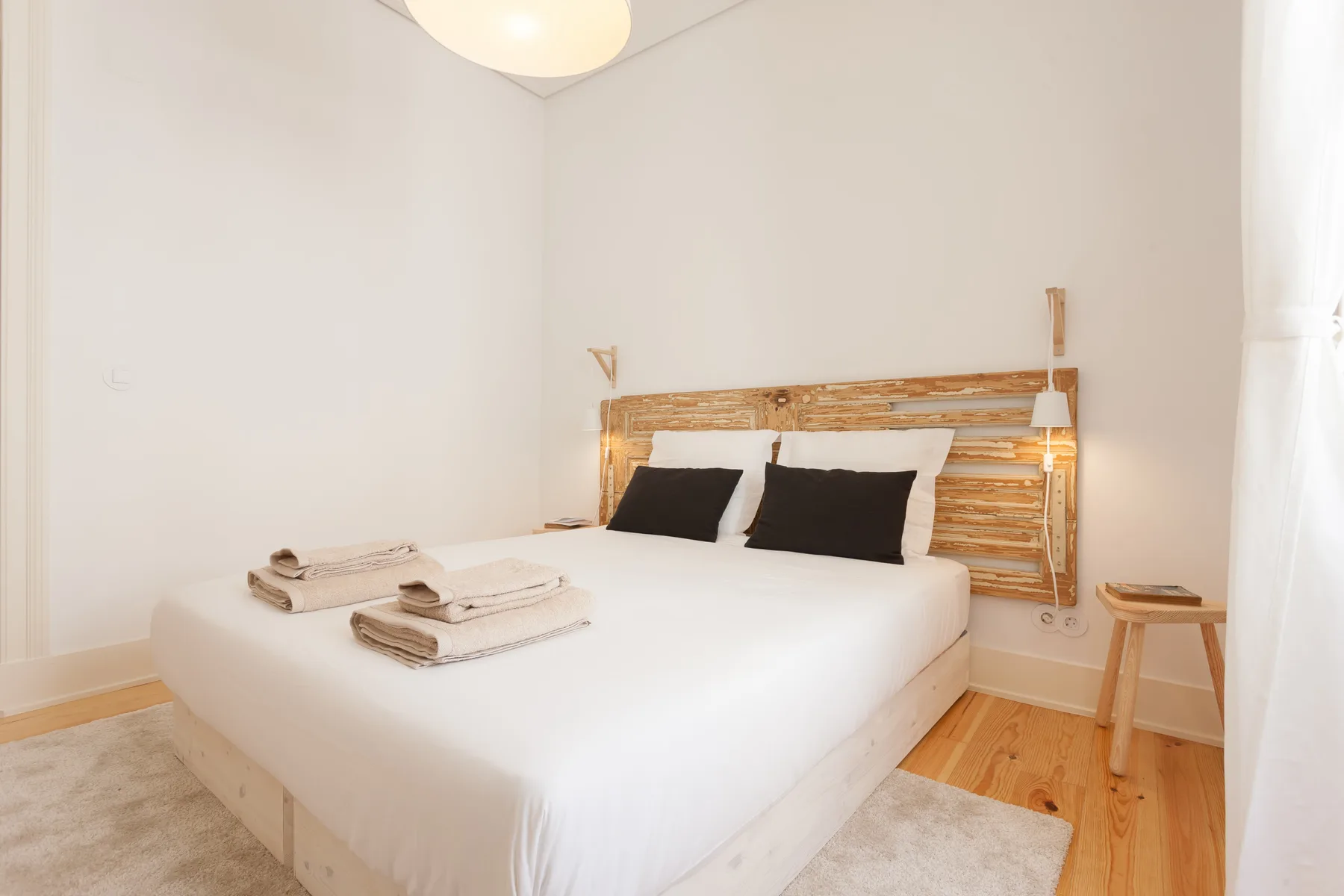 Un dormitorio luminoso con una cama bien hecha y un cabecero de madera.