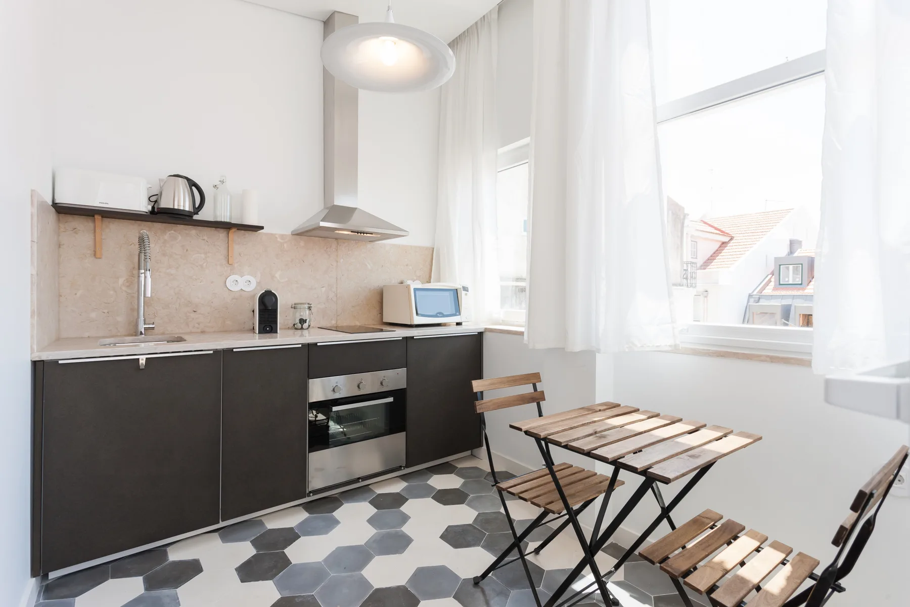 A compact kitchen with dark cabinets and a small wooden dining table by the window.