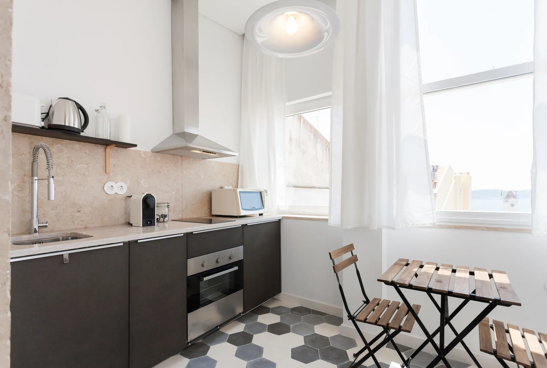 A bright kitchen with dark cabinets and a small dining table beside the windows.