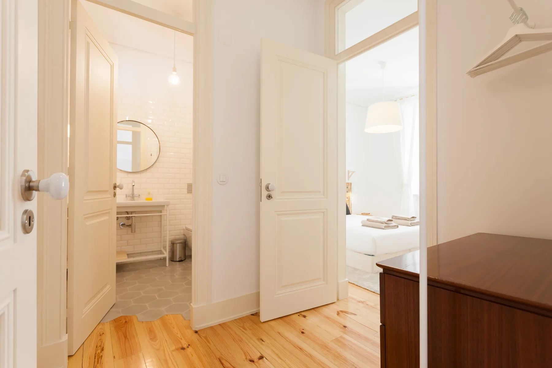 A bright apartment interior with open doors revealing a bathroom and a bedroom.