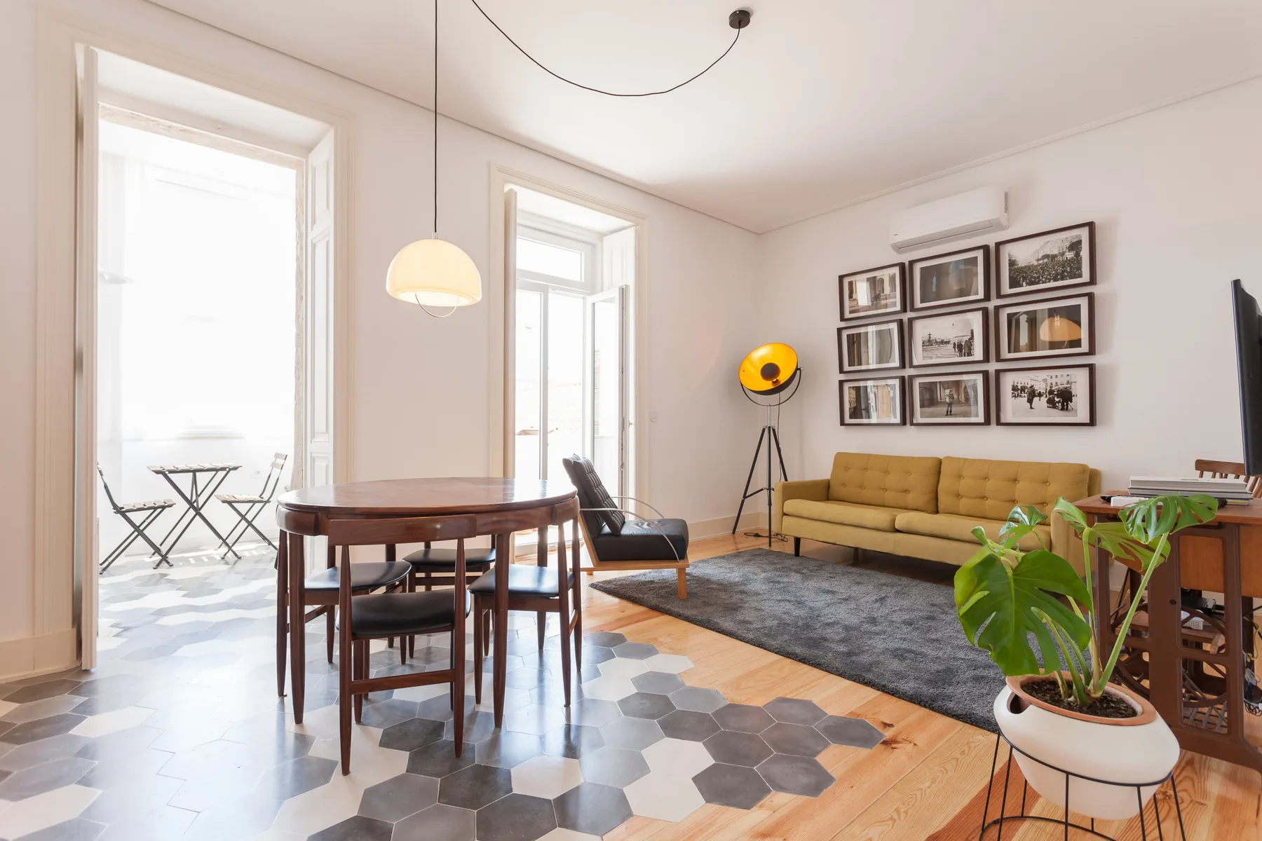Living and dining area with a seating space, framed pictures, and tall windows.