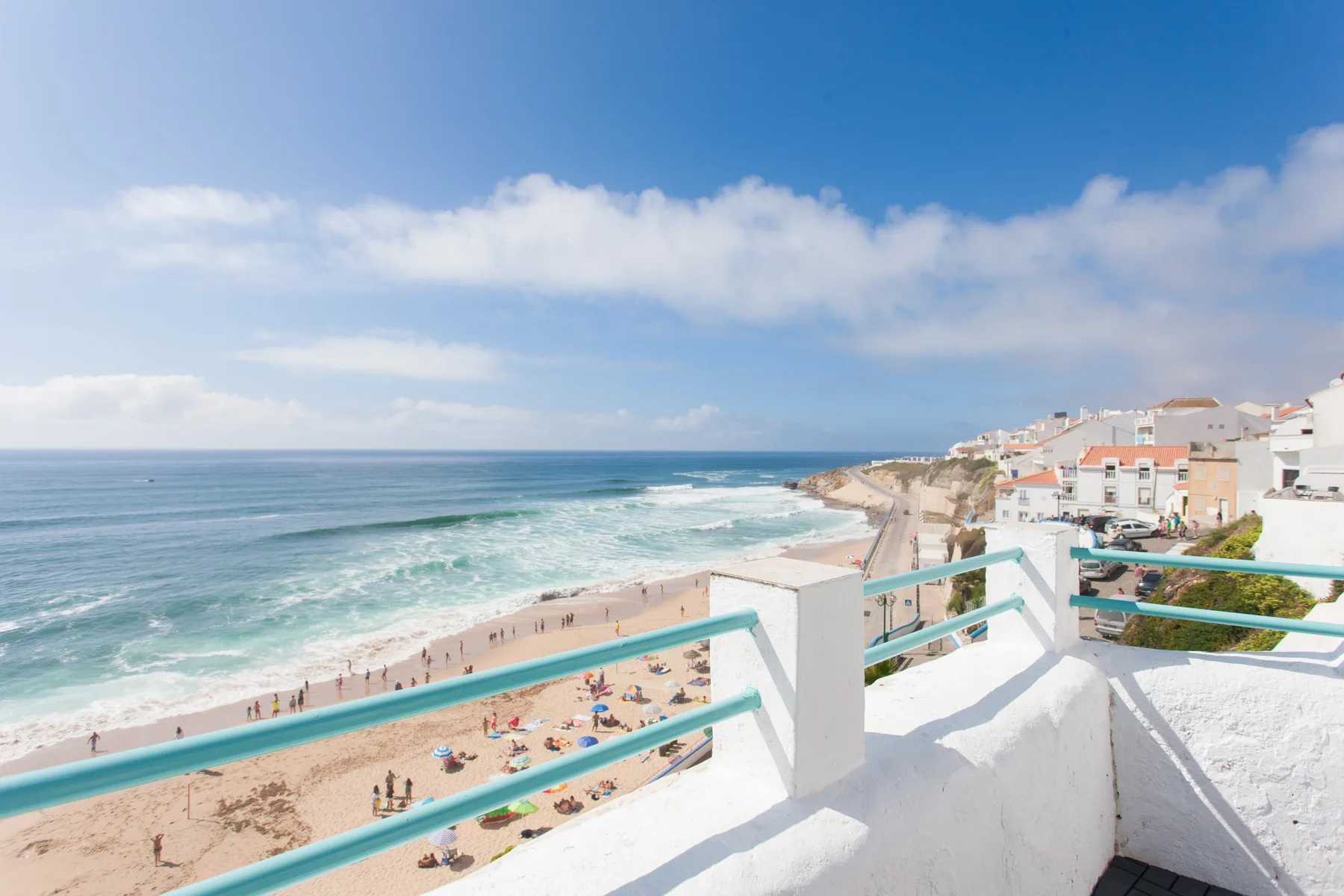 A seaside balcony overlooks a sandy beach and ocean waves.