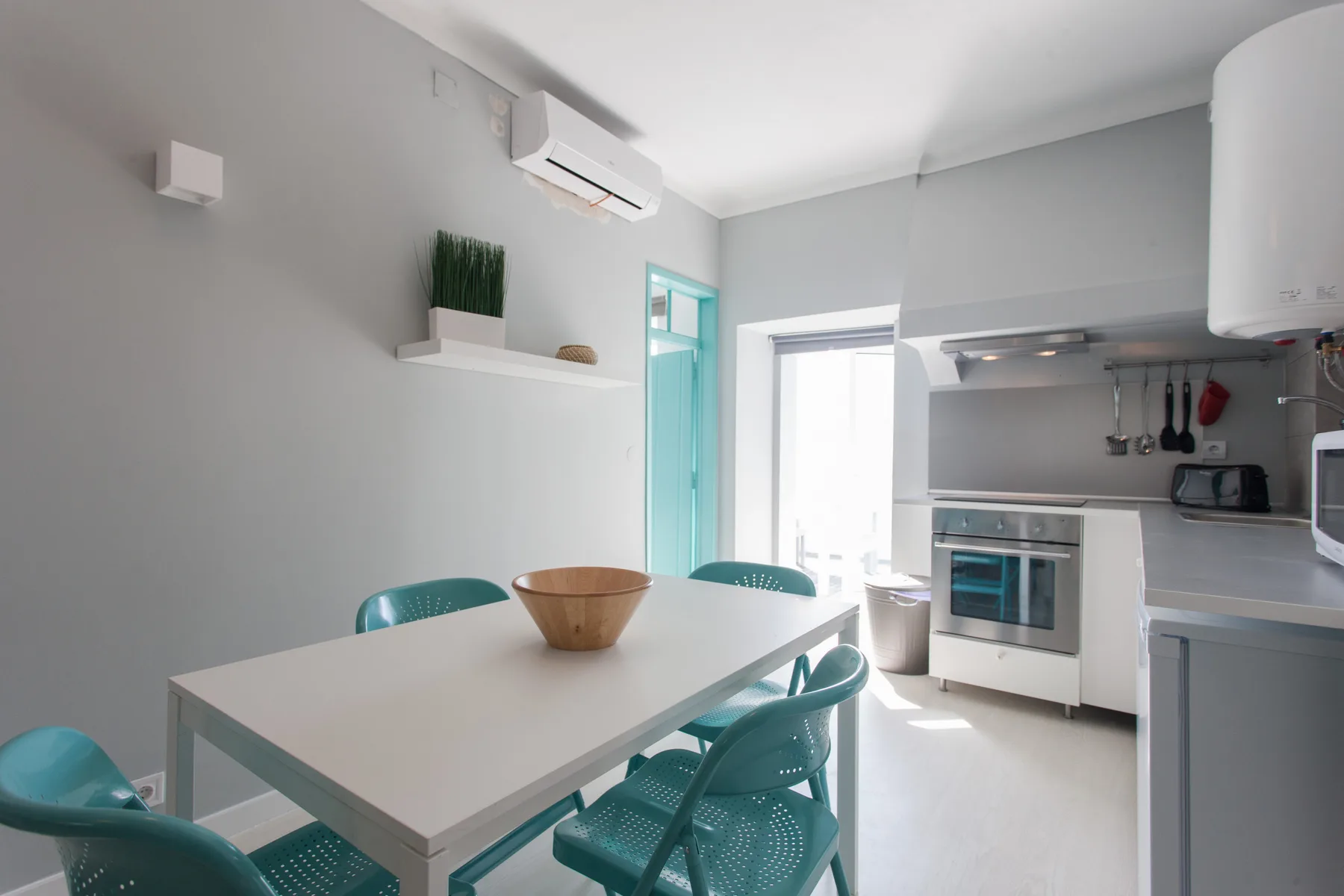 A bright kitchen and dining area with a table and turquoise seating.