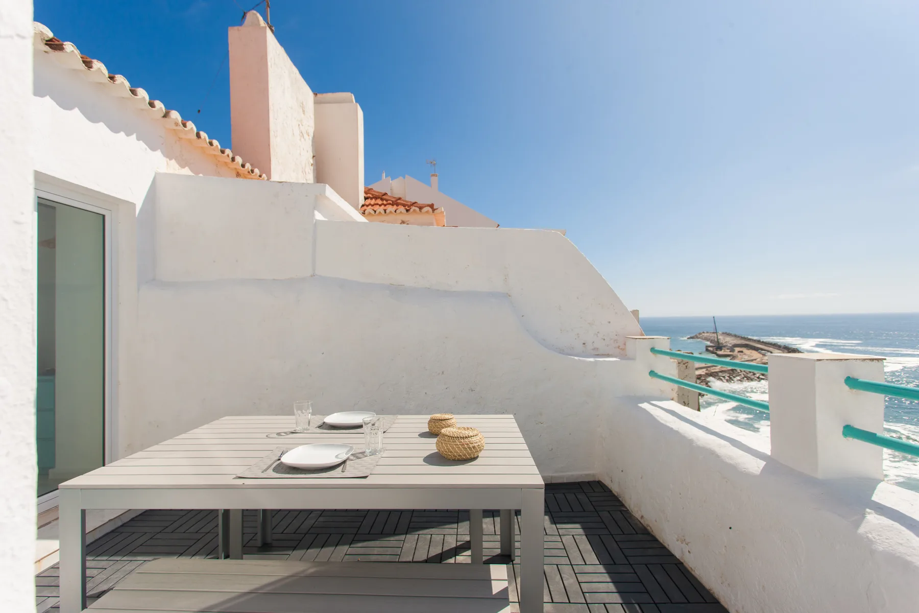 A rooftop terrace with a dining table overlooks the ocean.