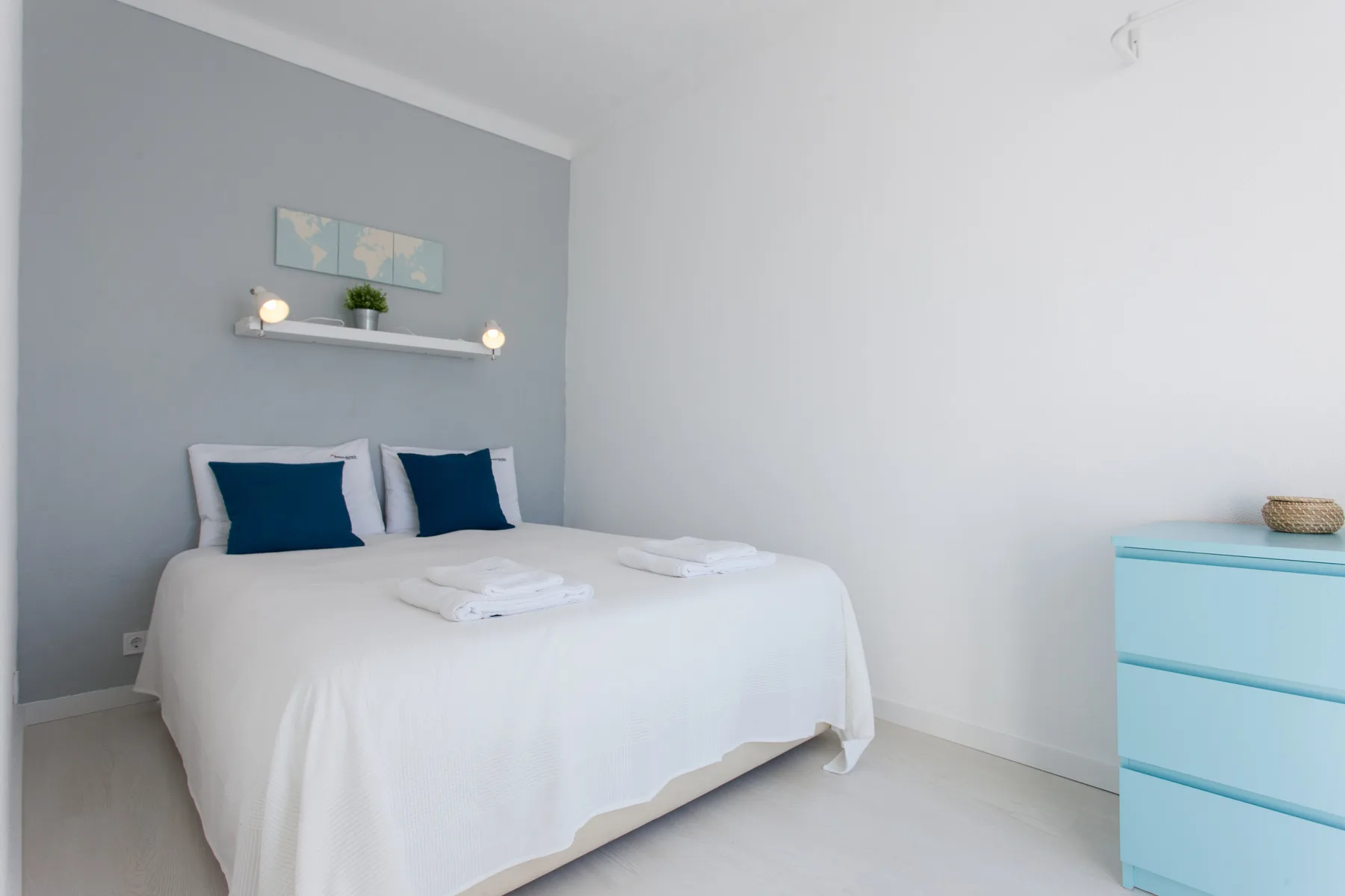 A bedroom with a white bed and blue accent pillows.