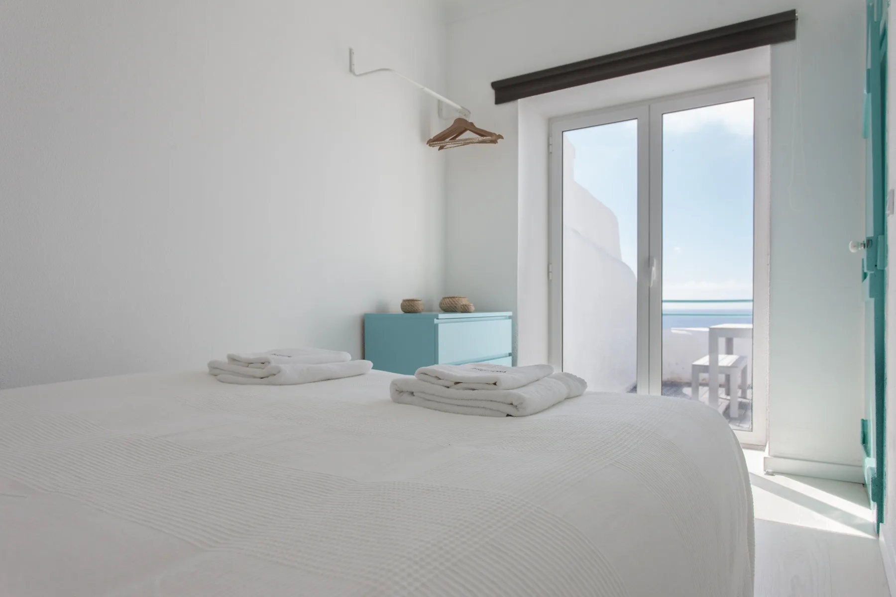 A bright bedroom with a bed and glass doors opening onto an ocean view.