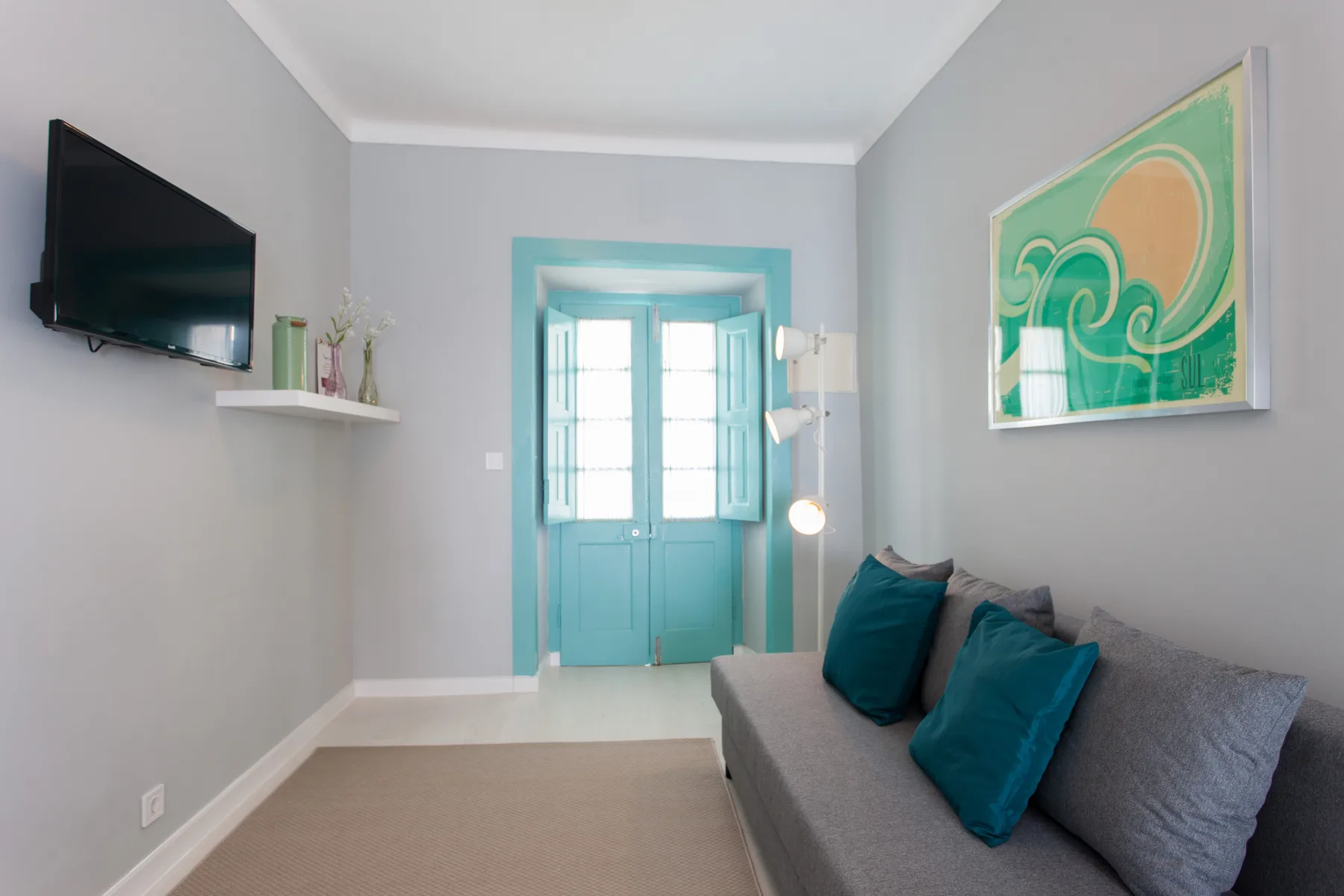 Living room with gray seating, teal cushions, and a television.