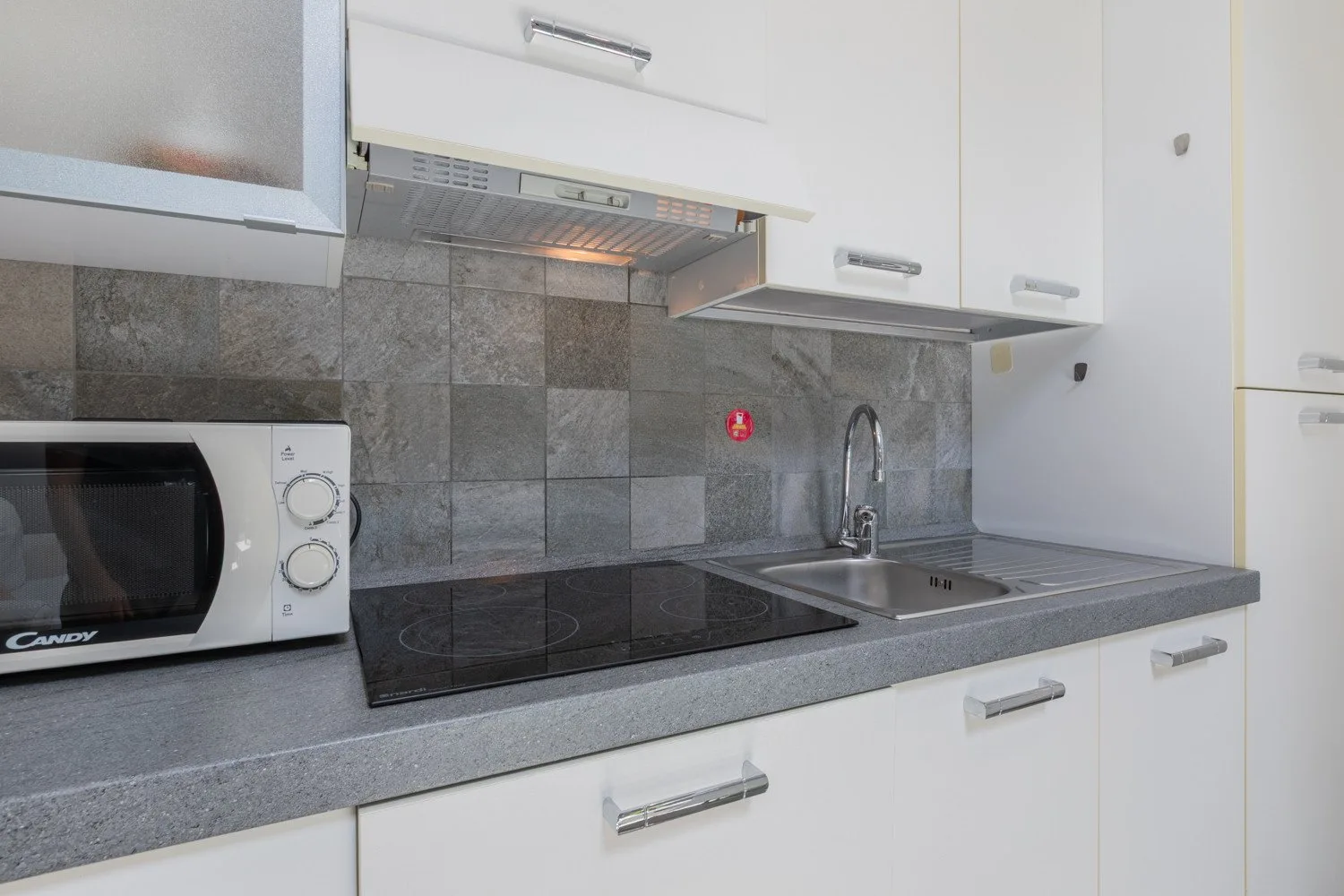 A modern kitchen counter with a microwave, stovetop, and sink.