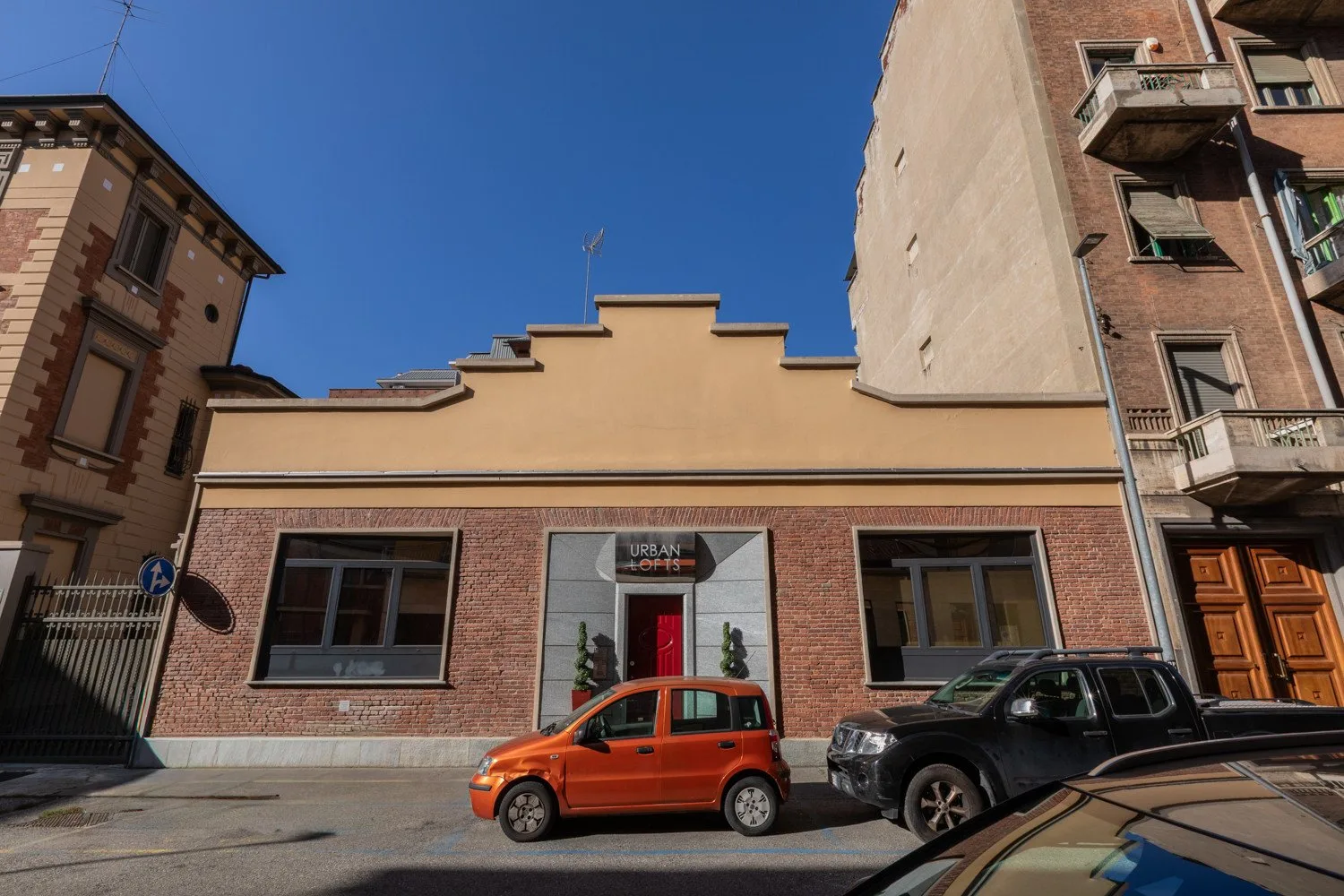 Un edificio bajo de ladrillo está en una calle urbana entre edificios más altos.