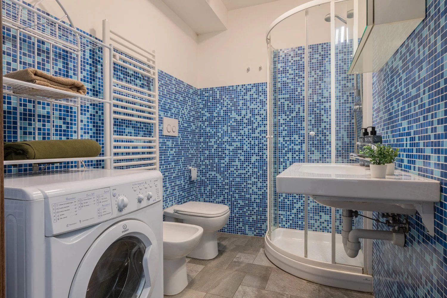 Un baño alicatado con ducha, inodoro y lavadora.