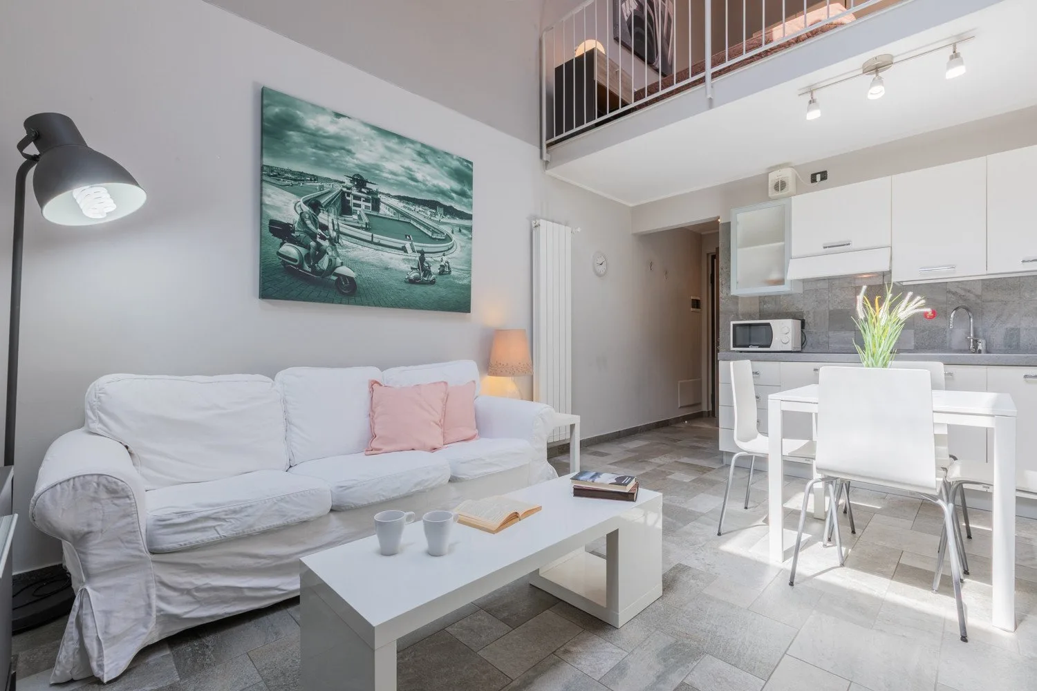 Una luminosa sala de estar y comedor con un sofá blanco y una cocina contigua.