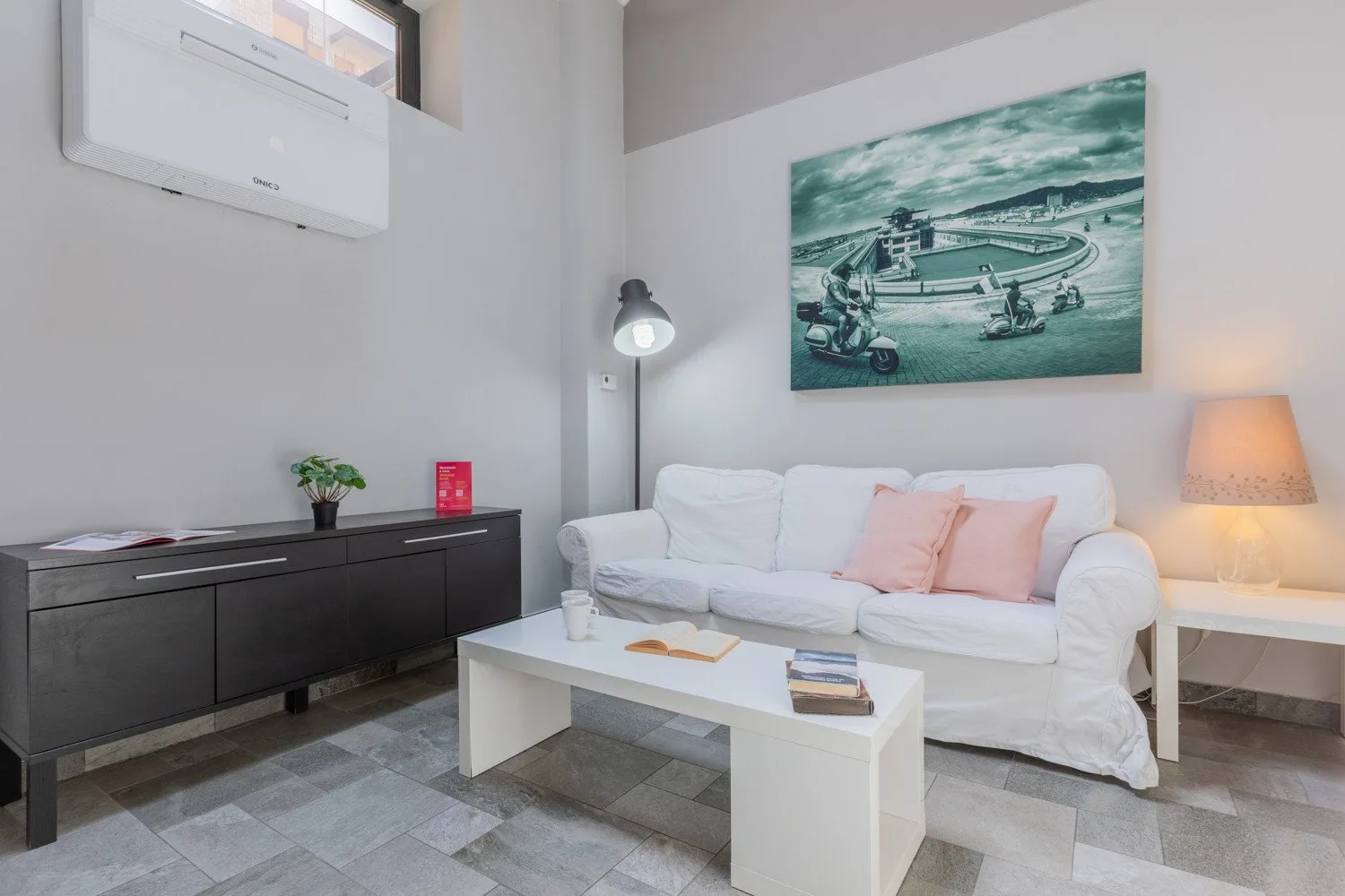 Una sala de estar con asientos blancos, una mesa de centro y arte en la pared.