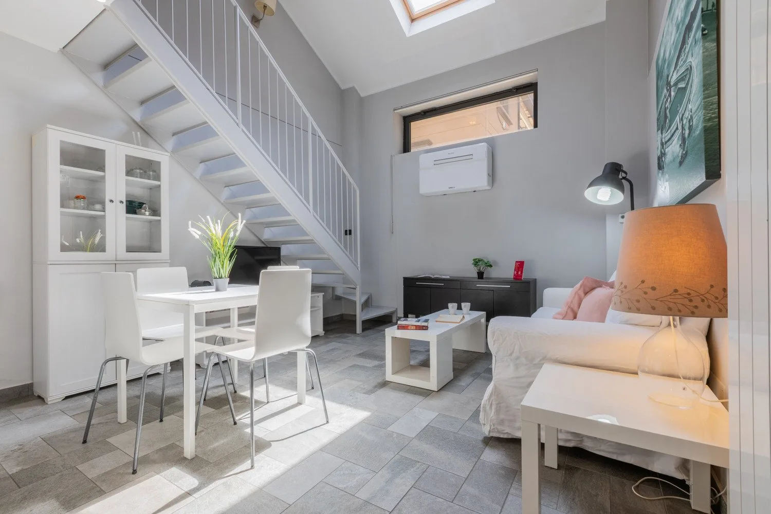 Una luminosa sala de estar y comedor con escalera, mesa y asientos.