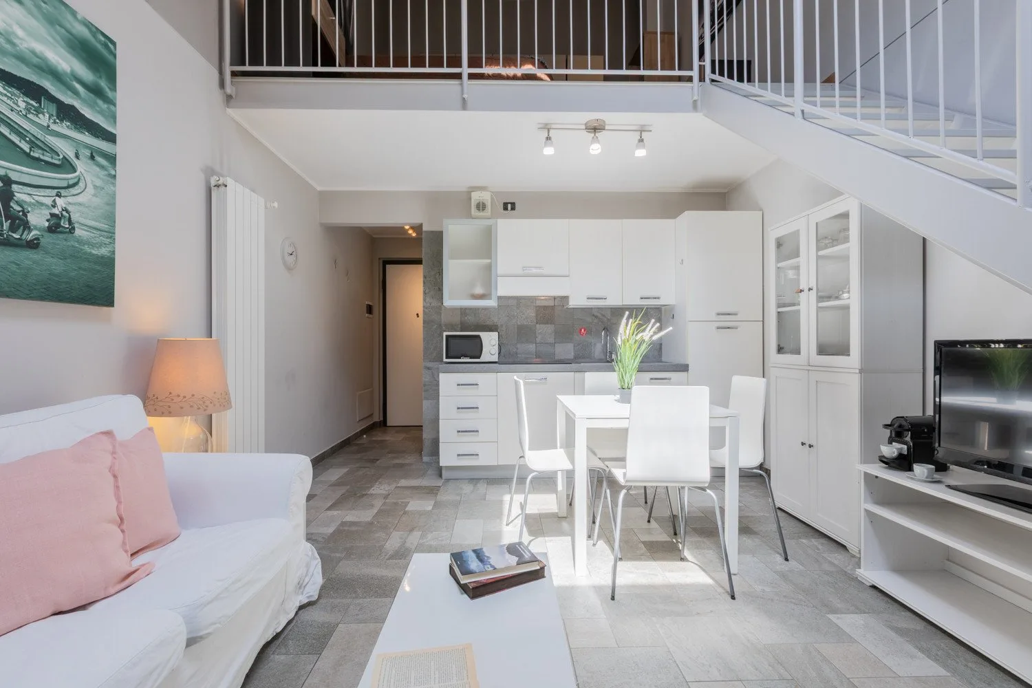 A bright open-plan living area with a dining table beneath a mezzanine.