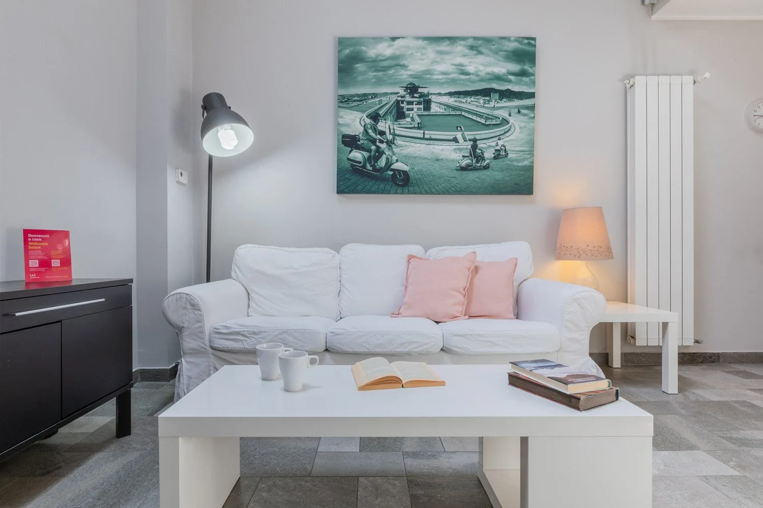 A bright living room with white seating, a coffee table, and wall art.