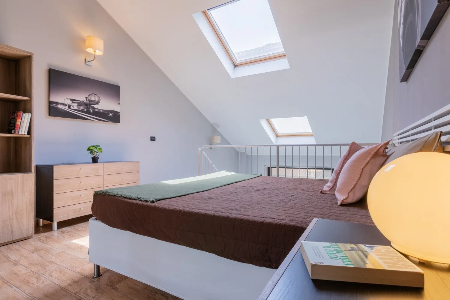 Un dormitorio con una cama bajo techos inclinados y tragaluces.