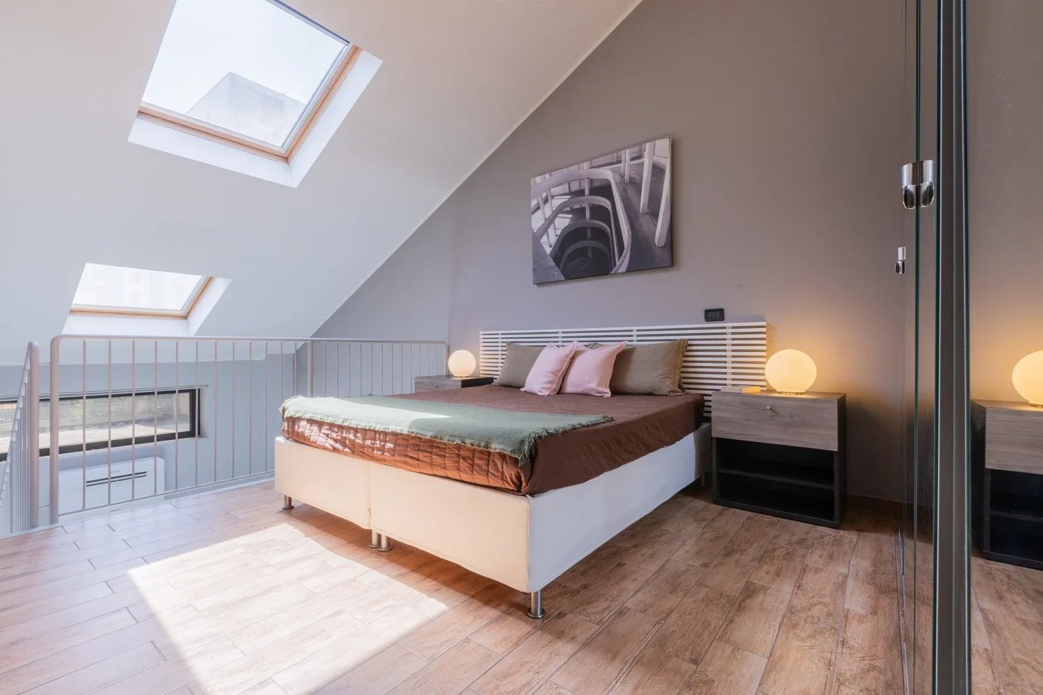 Un dormitorio con una cama bajo techos inclinados y tragaluces.