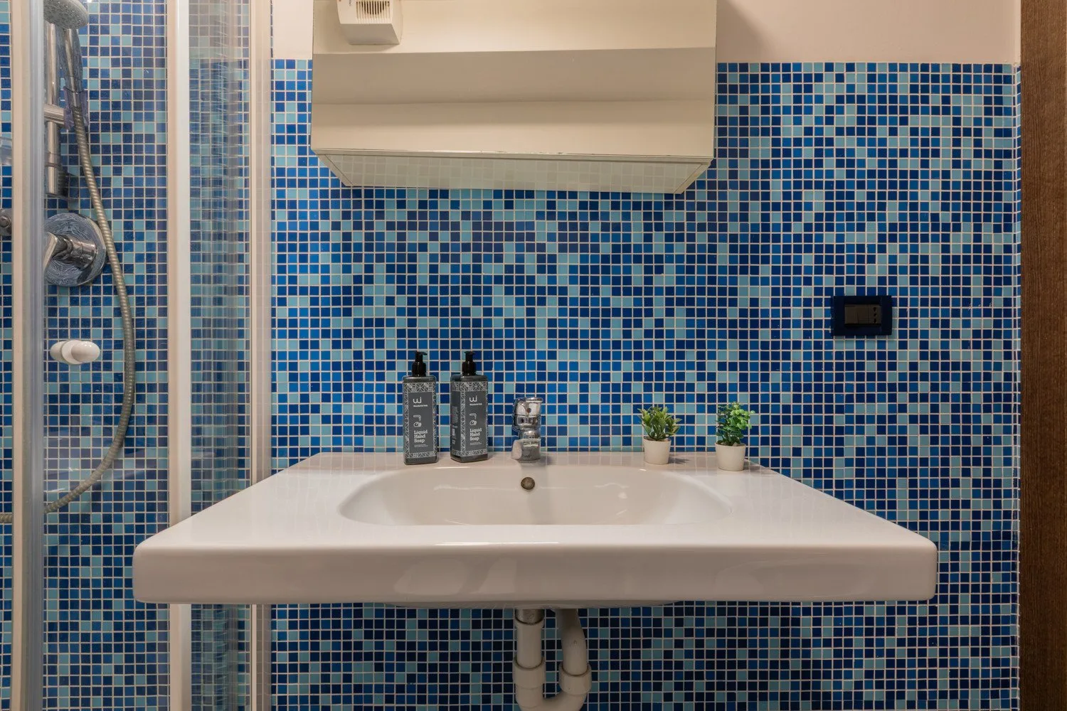 Un lavabo de baño con azulejos, artículos de aseo y un armario con espejo en la pared.