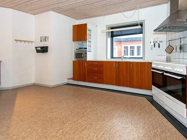 Una cocina con gabinetes de madera, una ventana y una estufa.