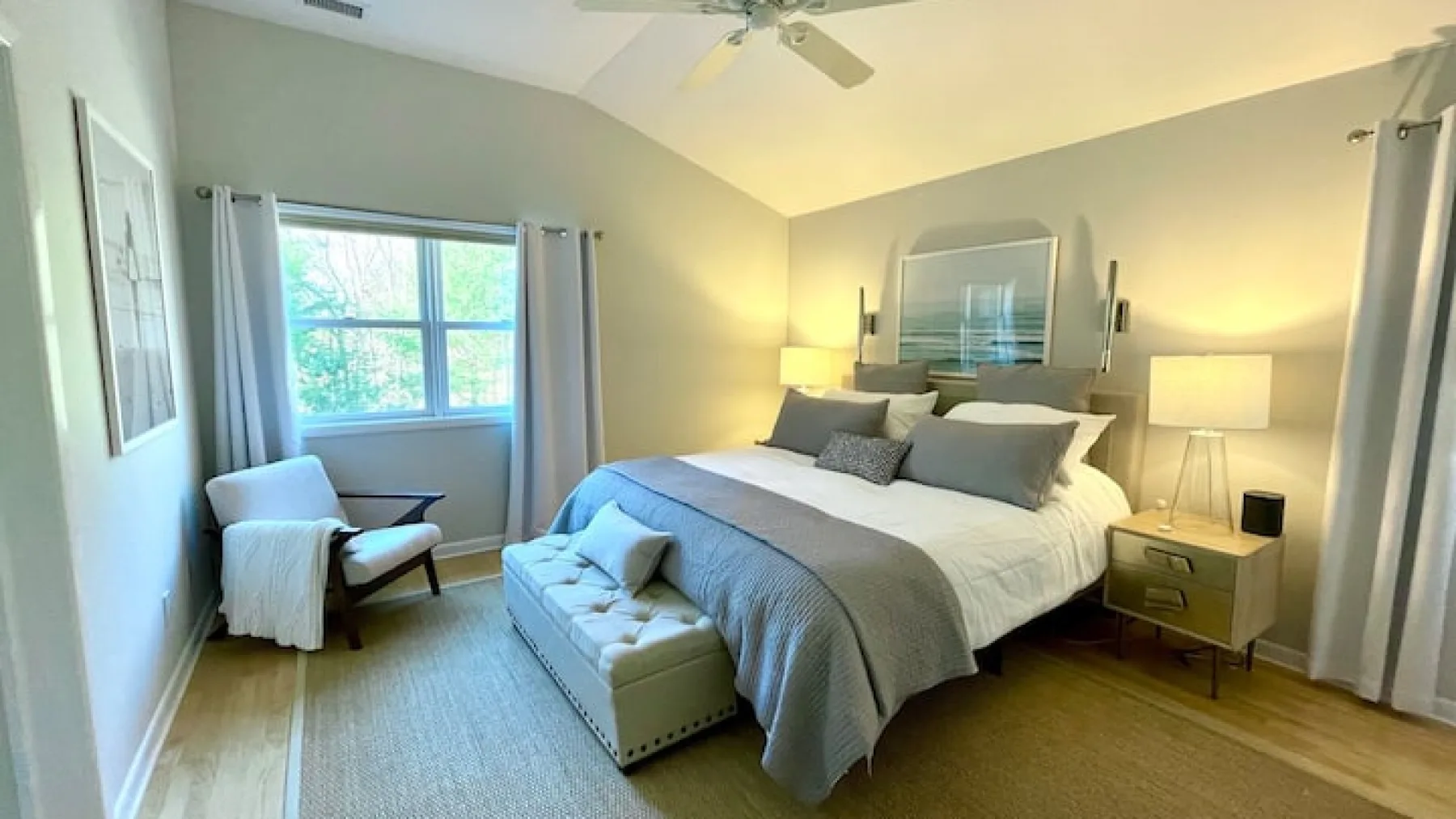 Un dormitorio luminoso con una cama, asientos y una ventana.