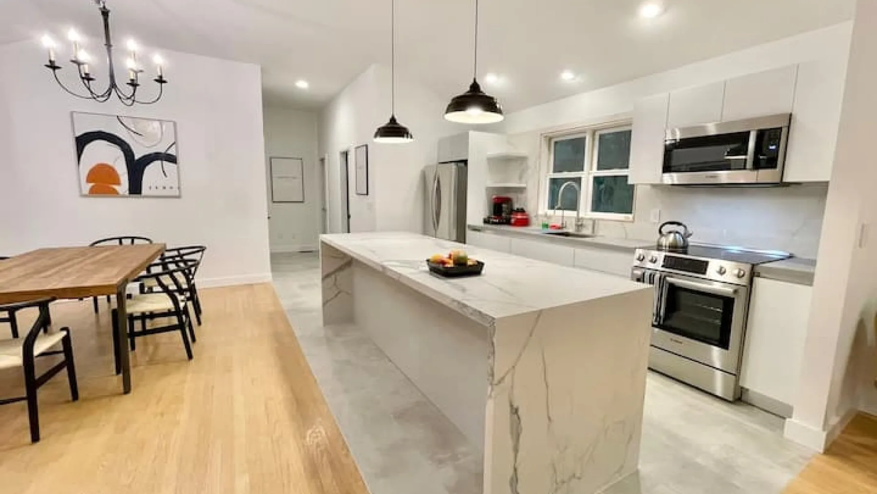 Una cocina luminosa con comedor cuenta con una isla grande y una mesa de madera.