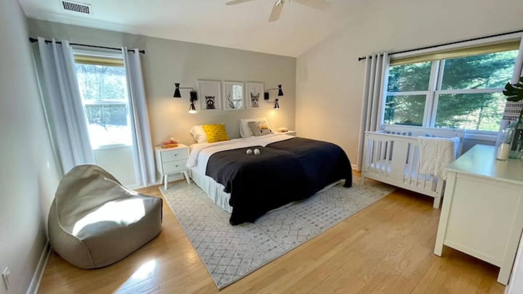 Un dormitorio con una cama, una alfombra clara y ventanas con vistas a la vegetación.