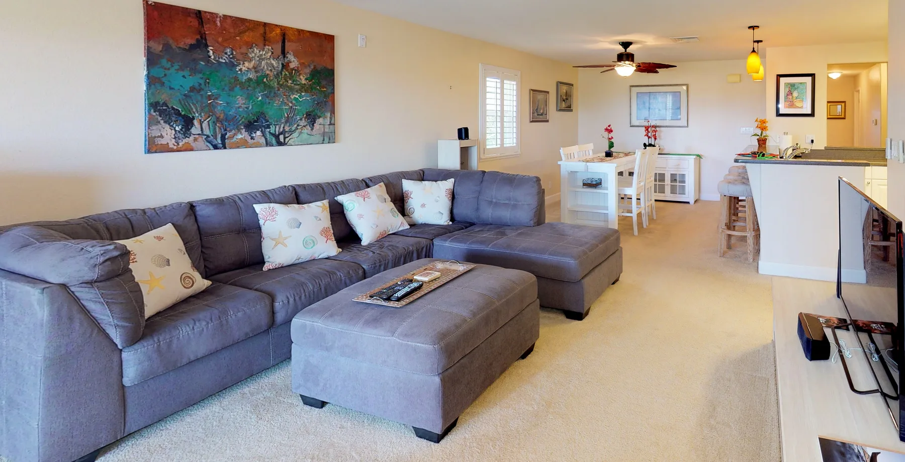 A living room with a sectional sofa and dining area in the background.