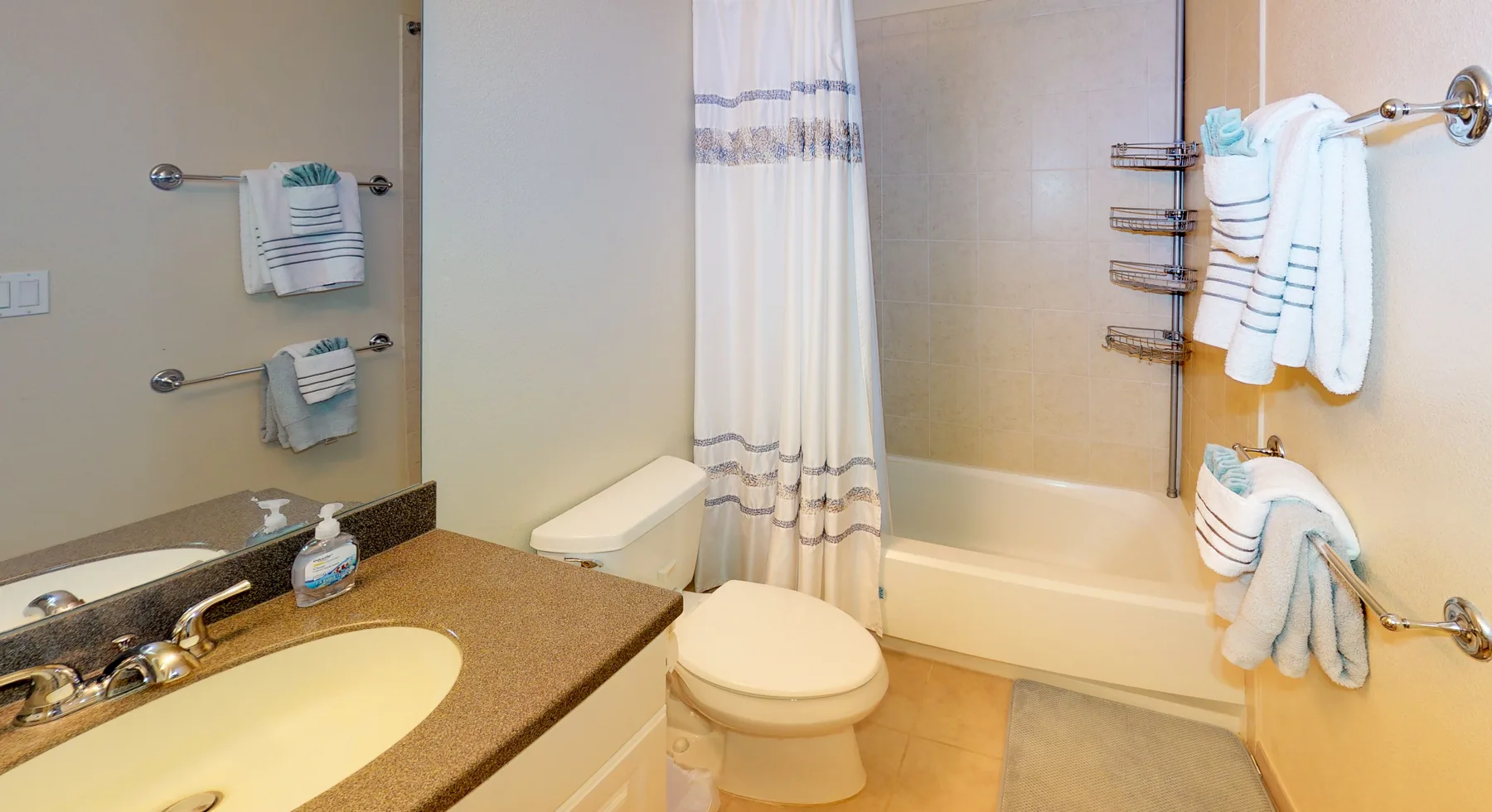 A bathroom with a bathtub, shower curtain, toilet, and sink.