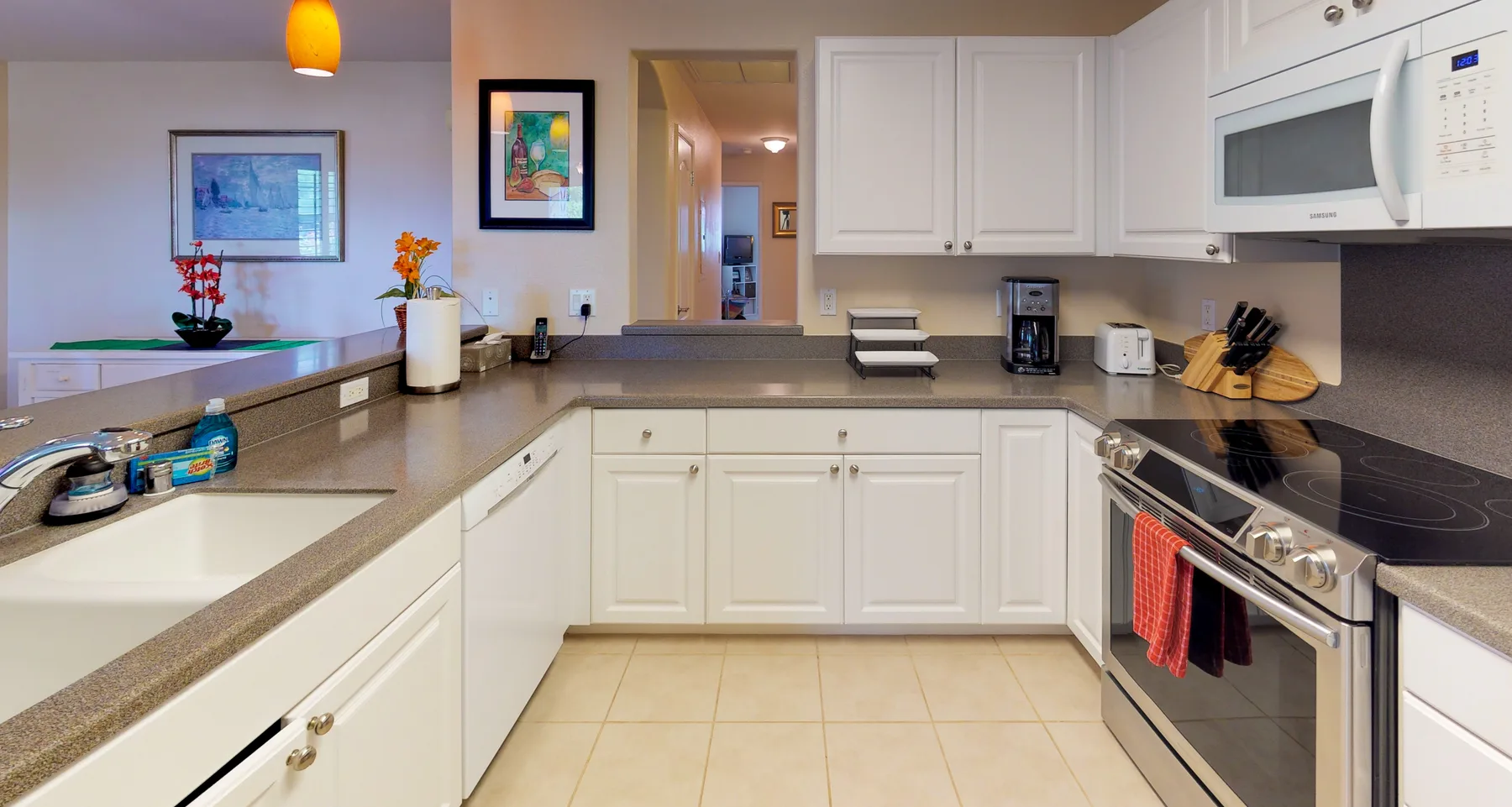 A bright kitchen with white cabinetry, light countertops, and cooking appliances.