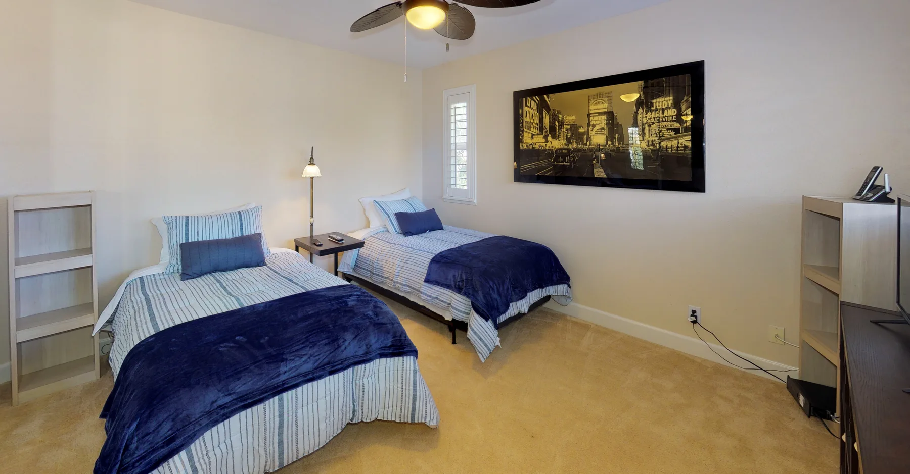 A bedroom with two twin beds, blue bedding, and framed wall art.