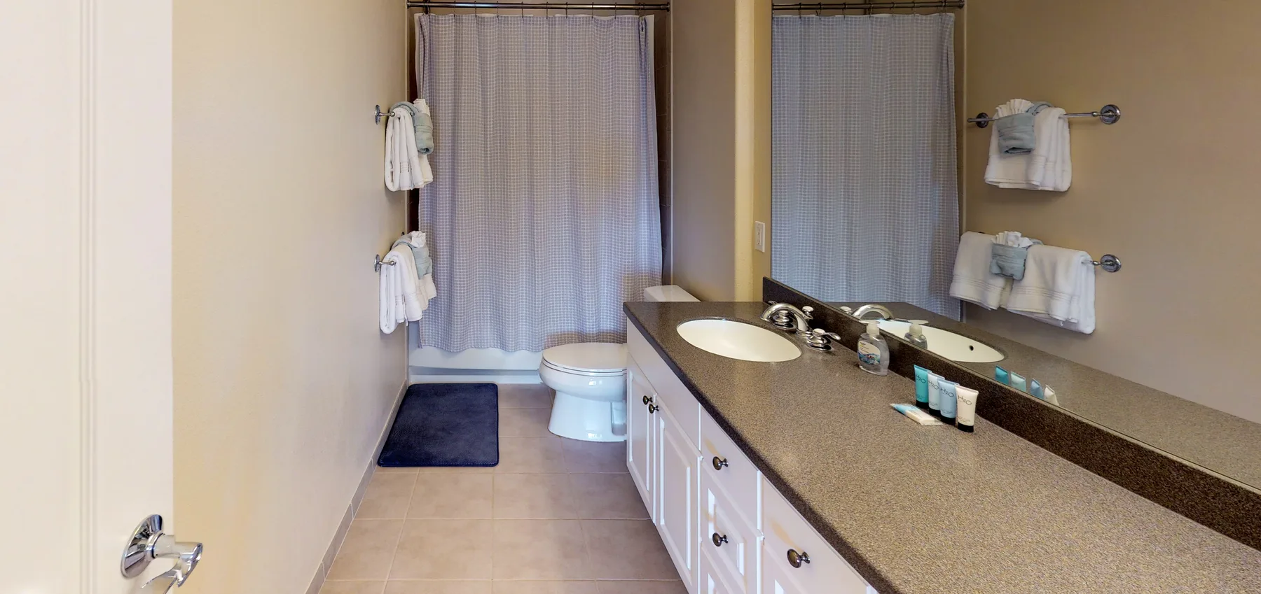 A bathroom with a long vanity, mirror, and shower area.
