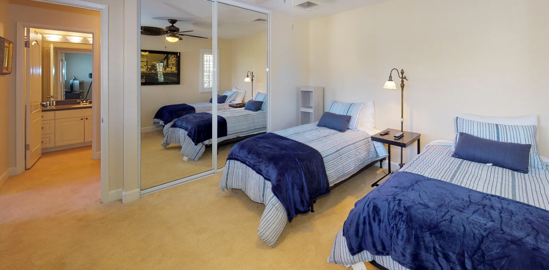 A bedroom with two beds dressed in blue and striped bedding.