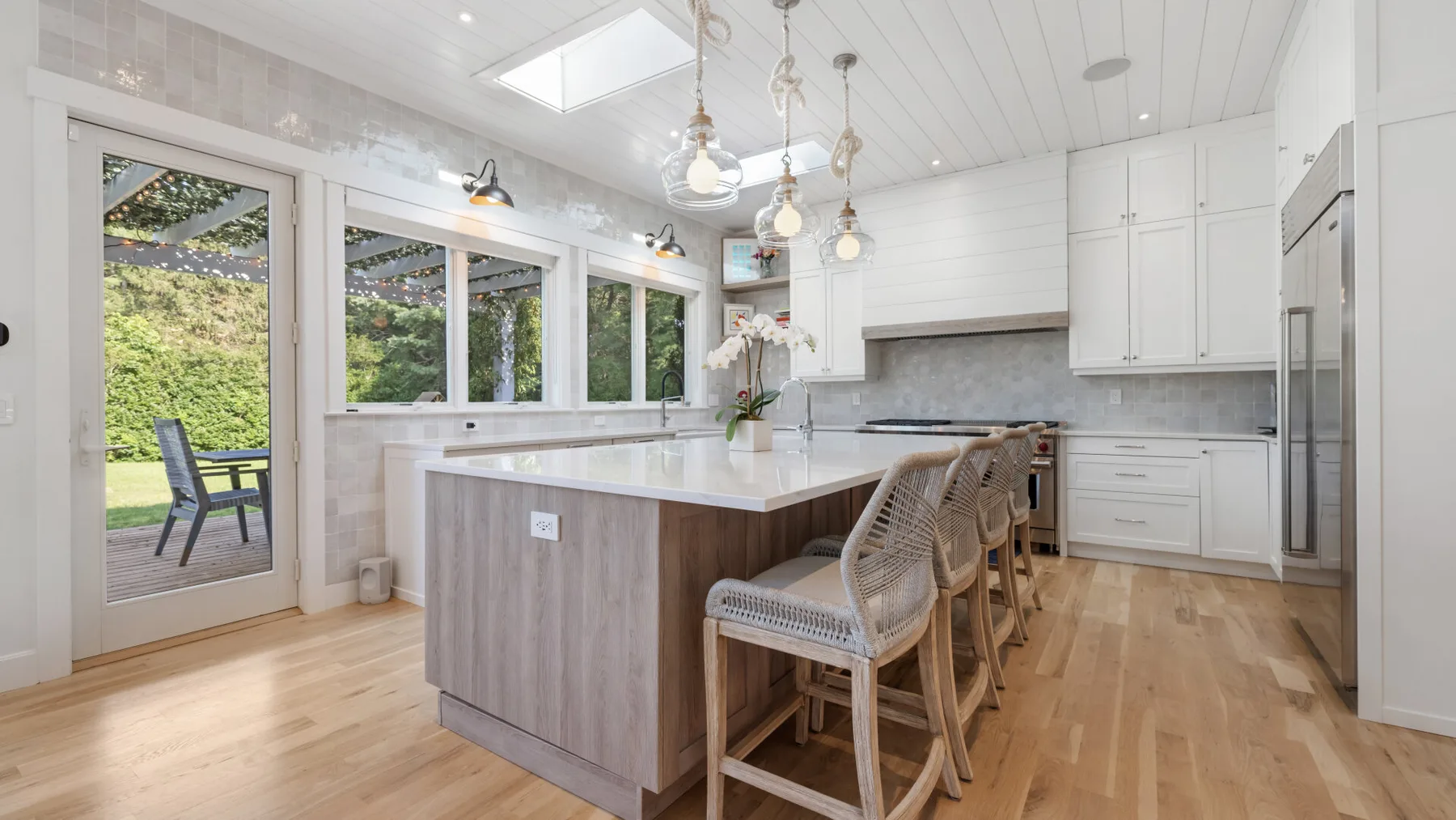 Una cocina luminosa con una isla central, asientos de barra y ventanas amplias.