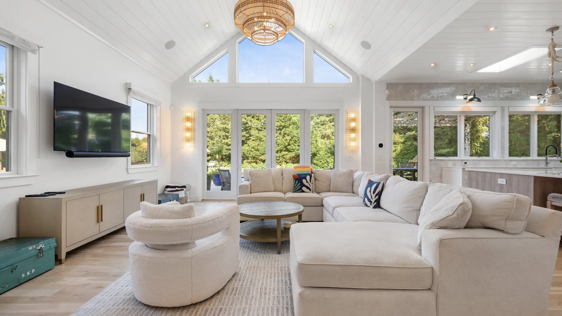 A bright living room with seating, a television, and large windows.