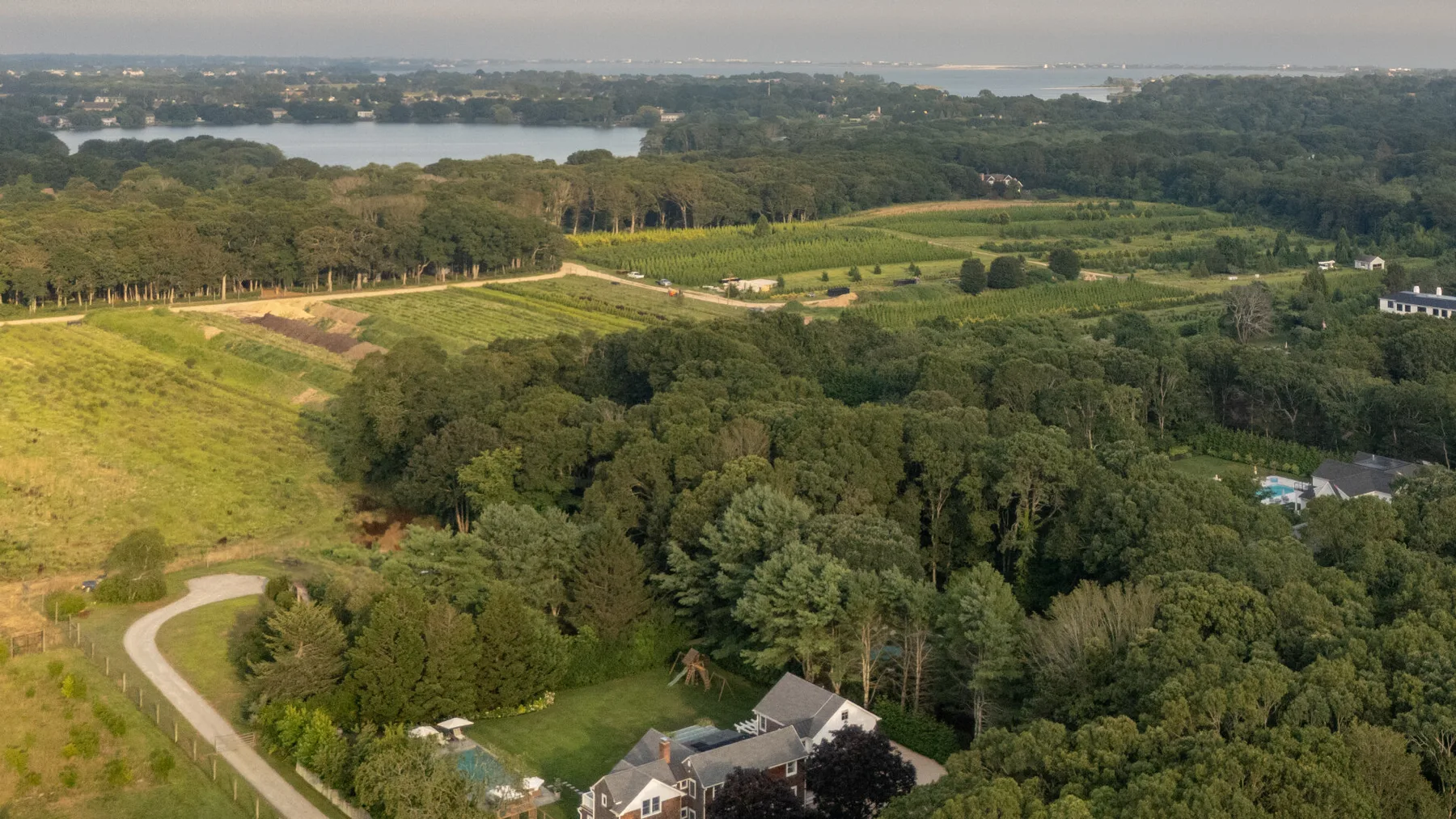 Vista aérea de una zona rural boscosa con campos abiertos y un camino sinuoso.