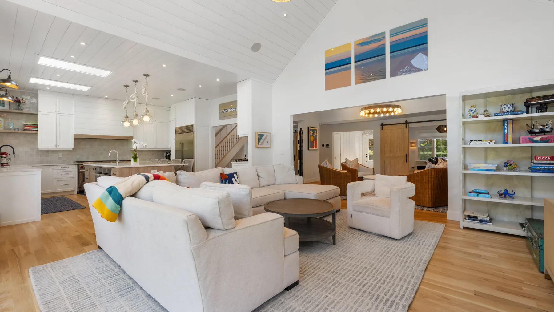 A bright open-plan living room with seating arranged around a coffee table.