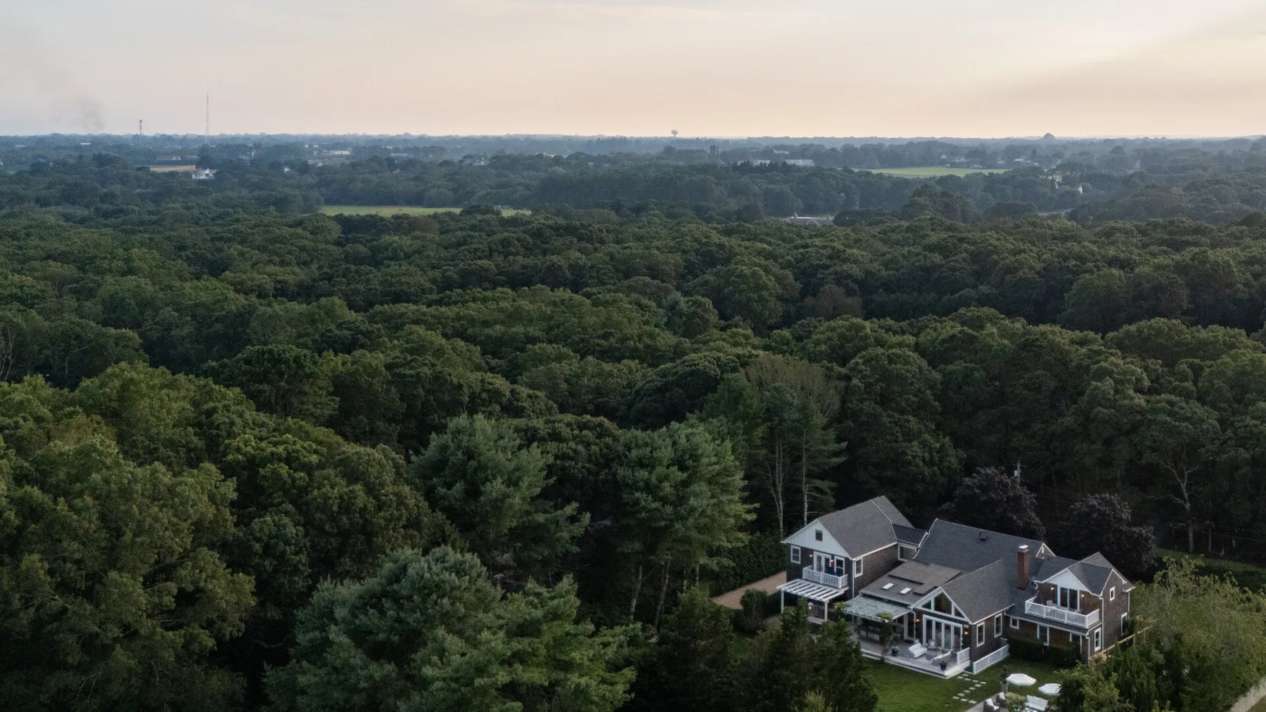 Vista aérea de una casa grande junto a un extenso bosque.